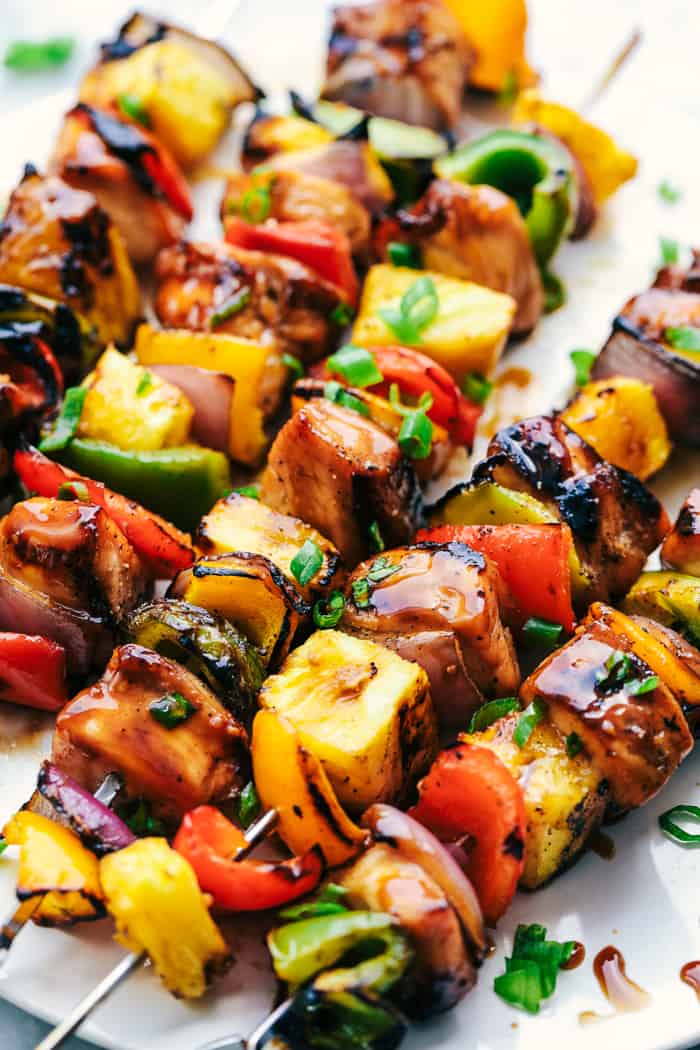 Grilled Hawaiian Teriyaki Chicken Skewers marinate in the very best homemade hawaiian teriyaki sauce! Loaded with peppers, fresh pineapple and red onions, these make an incredible and vibrant meal!ย Hawaiian Teriyaki Chicken Skewers laid in rows.