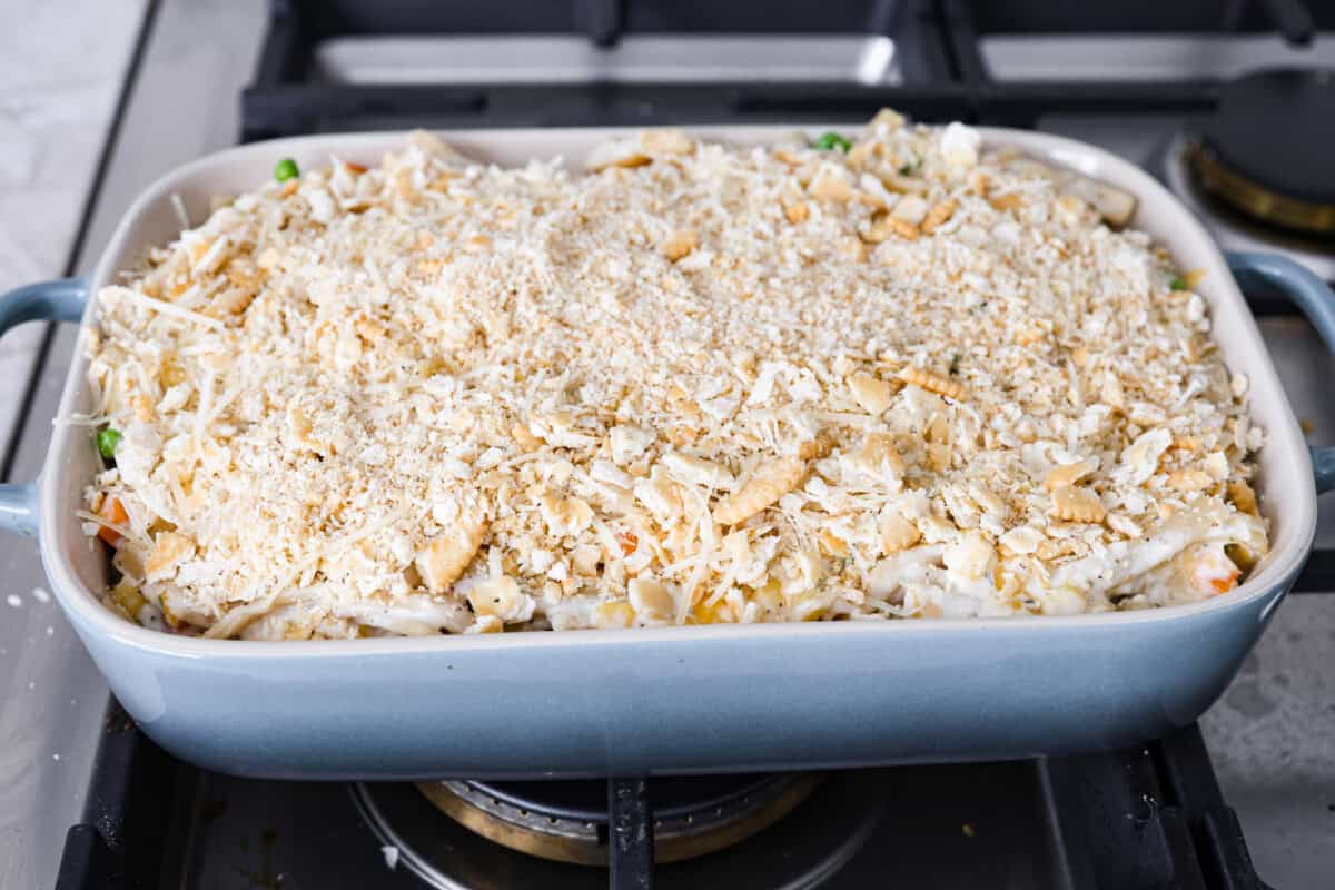 cooked chicken, corn, cream of chicken soup, milk, sour cream, onion flakes, Italian seasoning, garlic powder, salt, pepper, and cheddar cheese. Angle shot of the creamy chicken noodle casserole ready to be topped with aluminum foil and into the oven.