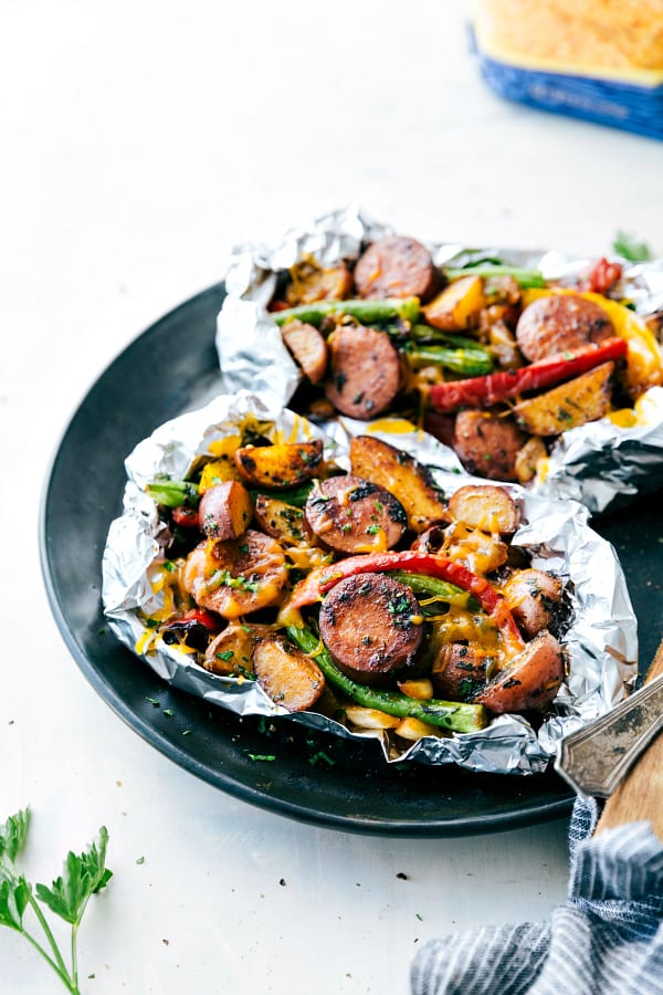 Cheesy Sausage Potato Foil Packets are simple to assemble and packed with sausage, potatoes, veggies and cheese. These are perfect for a camping trip or quick dinner and are sure to be a hit!ย Cheesy Sausage Potato Foil Packets on a black plate.
