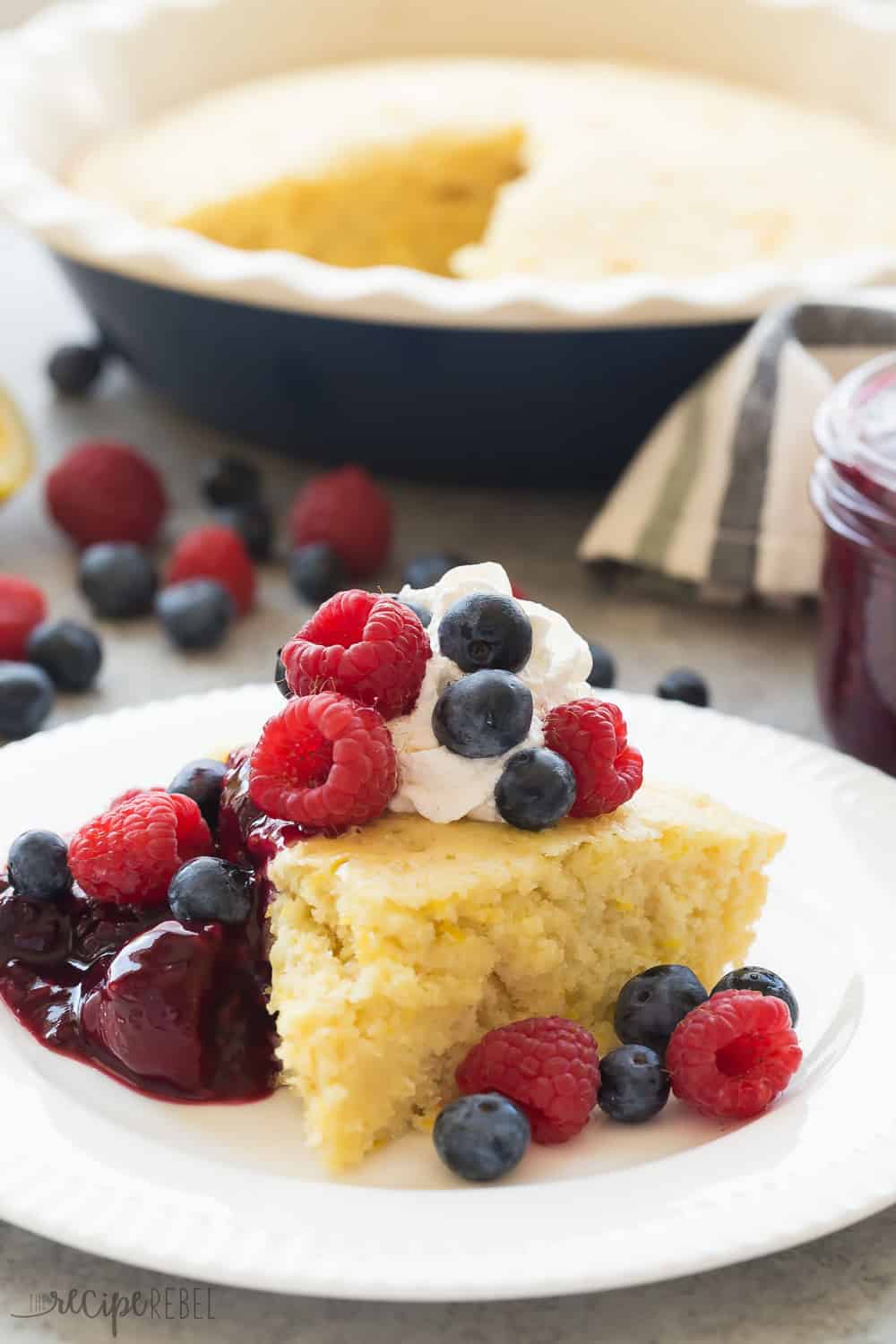 This Lemon Baked Pancake with Berry Sauce is such an easy breakfast for serving a crowd! Perfect for all your holiday brunches. This Lemon Baked Pancake with Berry Sauce slice on a white plate.