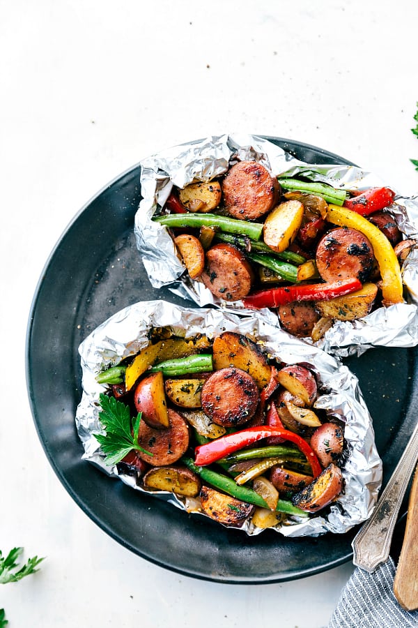 Cheesy Sausage Potato Foil Packets are simple to assemble and packed with sausage, potatoes, veggies and cheese. These are perfect for a camping trip or quick dinner and are sure to be a hit!ย Cheesy Sausage Potato Foil Packets on a black plate.