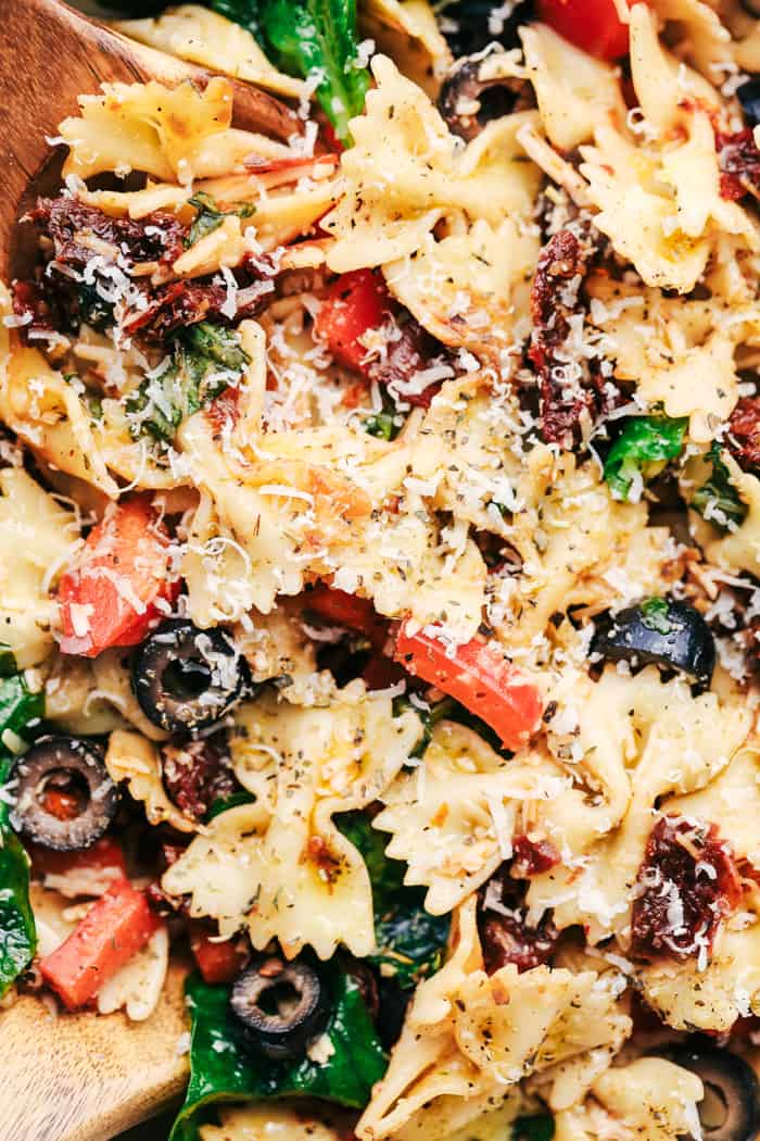 Tuscan Pasta Salad is an easy pasta salad with sun dried tomatoes, peppers spinach, and olives tossed in a tangy dressing. This pasta salad is perfect for your next potluck!ย Tuscan Pasta Salad close up.