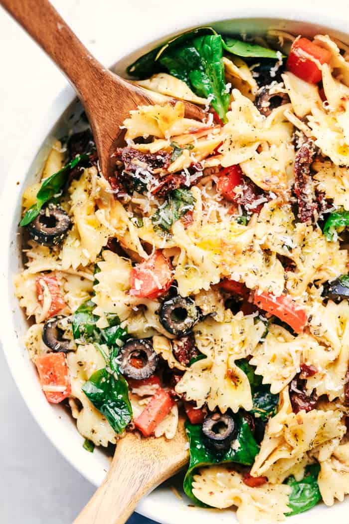 Tuscan Pasta Salad is an easy pasta salad with sun dried tomatoes, peppers spinach, and olives tossed in a tangy dressing. This pasta salad is perfect for your next potluck!ย Tuscan Pasta Salad in a bowl.