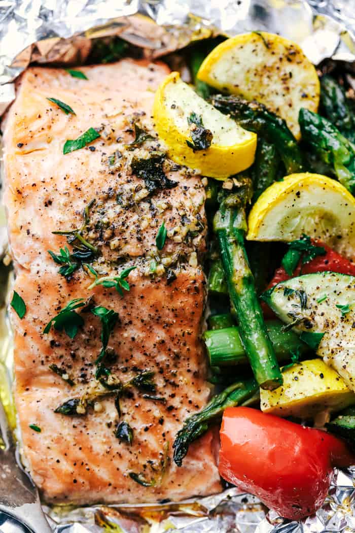 Butter Garlic Herb Salmon Foil Packets are made with tender and flaky salmon with fresh summer veggies. They cook to perfection with the best garlic herb compound and will become a family favorite! Butter Garlic Herb Salmon Foil Packets close up.