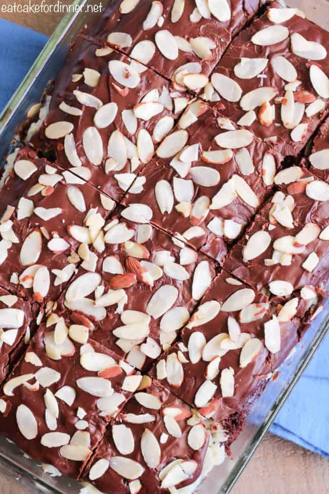 Almond Joy Poke Cake has all of the things that you love about an almond joy candy bar turned into a decadent cake! This cake is irresistible and will satisfy your chocolate craving! Finished almond joy poke cake in pan with slices cut.