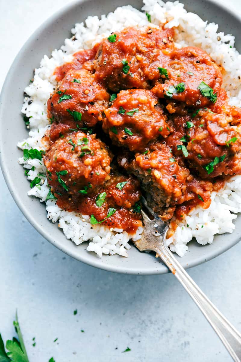 Slow Cooker Porcupine Meatballs are hearty and delicious meatballs filled with rice and served with a rich tomato sauce. This is a classic meal that the family will love!!ย Slow Cooker Porcupine Meatballson rice in a gray plate.
