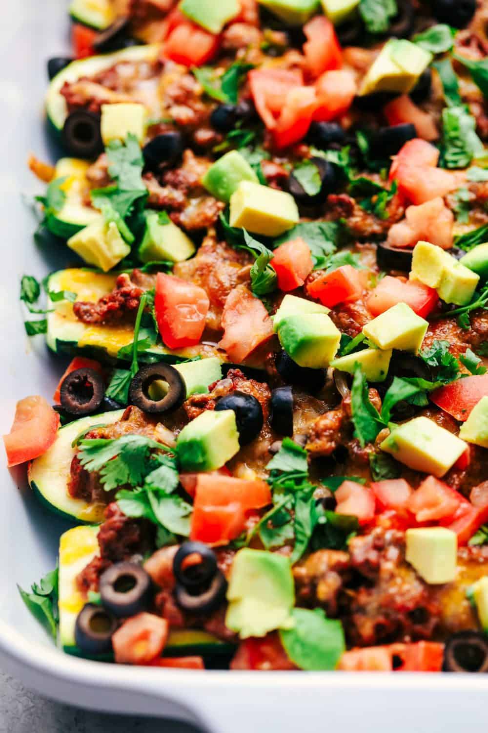 Taco Stuffed Zucchini Boats are loaded with taco seasoned ground beef, cheese and topped with your favorite toppings. These make a delicious low carb meal and are perfect for using up that zucchini! Taco Stuffed Zucchini Boats in pan
