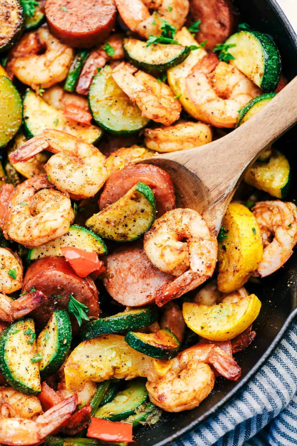 Cajun Shrimp and Sausage Vegetable Skillet is the BEST 20 minute meal packed with awesome cajun flavor with shrimp, sausage, and summer veggies. This makes a great low carb meal and is also great for meal prep! Cajun Shrimp and Sausage Vegetable Skillet with wooden spoon