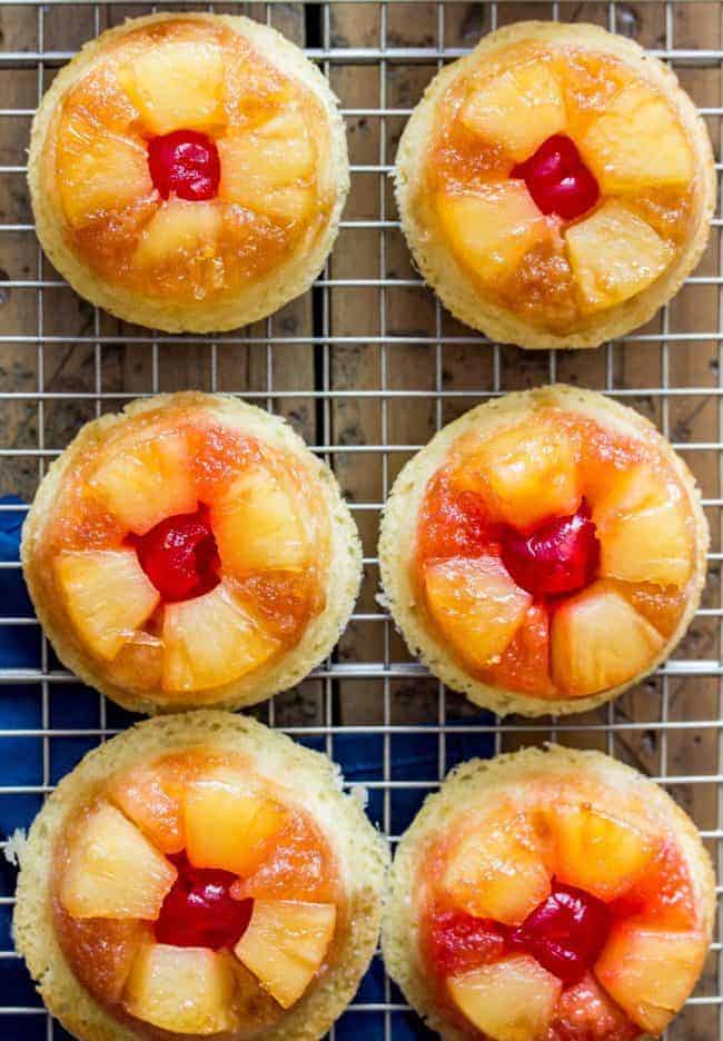 Sweet and simple pineapple upside down-cupcakes made entirely from scratch (donโt worry, theyโre easy!). With fluffy vanilla cupcake bases topped off with caramelized pineapple and maraschino cherries, these are a great new way to enjoy a classic recipe! Easy, from-scratch, pineapple upside-down cupcakes on a cooling rack.
