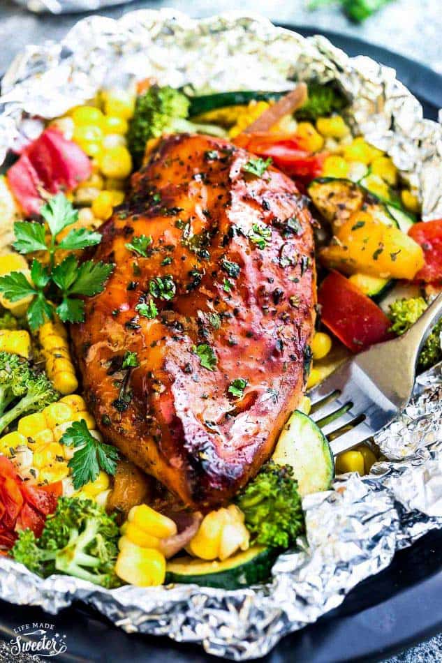 Grilled Honey Barbecue Chicken Foil Packets are the easiest summer meal with practically no clean-up! Perfectly tender chicken grilled with fresh summer veggies and coated in a delicious sweet and tangy barbecue sauce. Grilled Honey Barbecue Chicken Foil Packets close up.