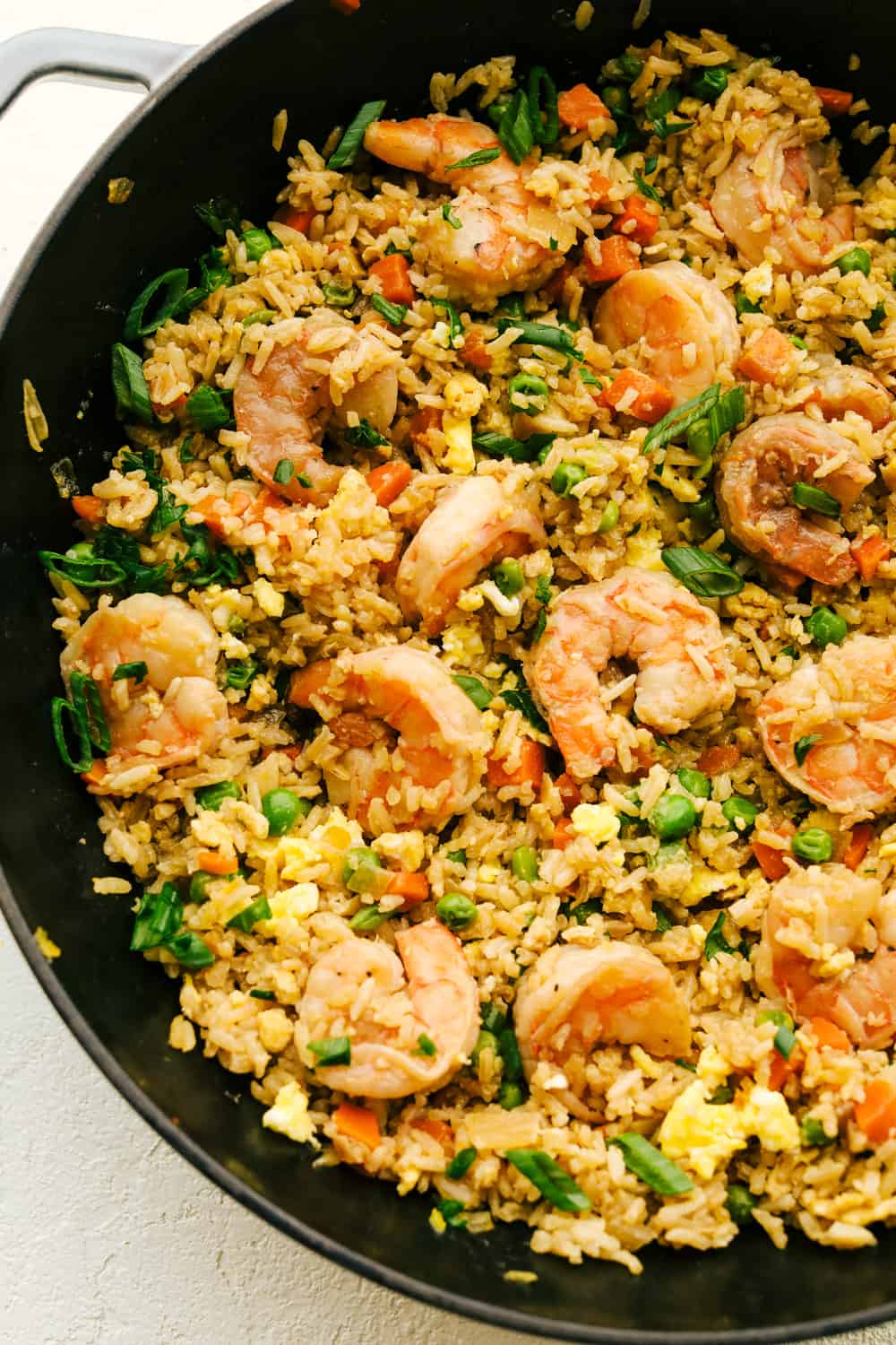 Skip the takeout! This shrimp fried rice is faster, fresher, and way more flavorful! Juicy shrimp, tender veggies, fluffy rice, and scrambled eggs all come together in one irresistible skillet meal. Close up of Shrimp fried rice in a pan.
