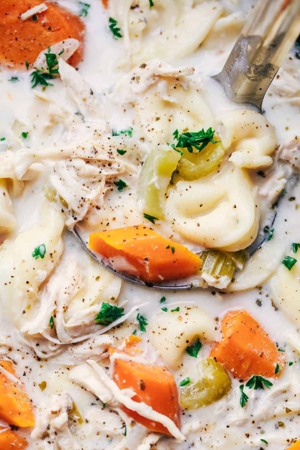 Slow Cooker Creamy Chicken Tortellini Soup is such a delicious and comforting soup. Loaded with carrots, celery, onion, chicken and tortellini, this creamy soup will become a favorite!ย Slow Cooker Creamy Chicken Tortellini Soup being scooped up by a spoon.
