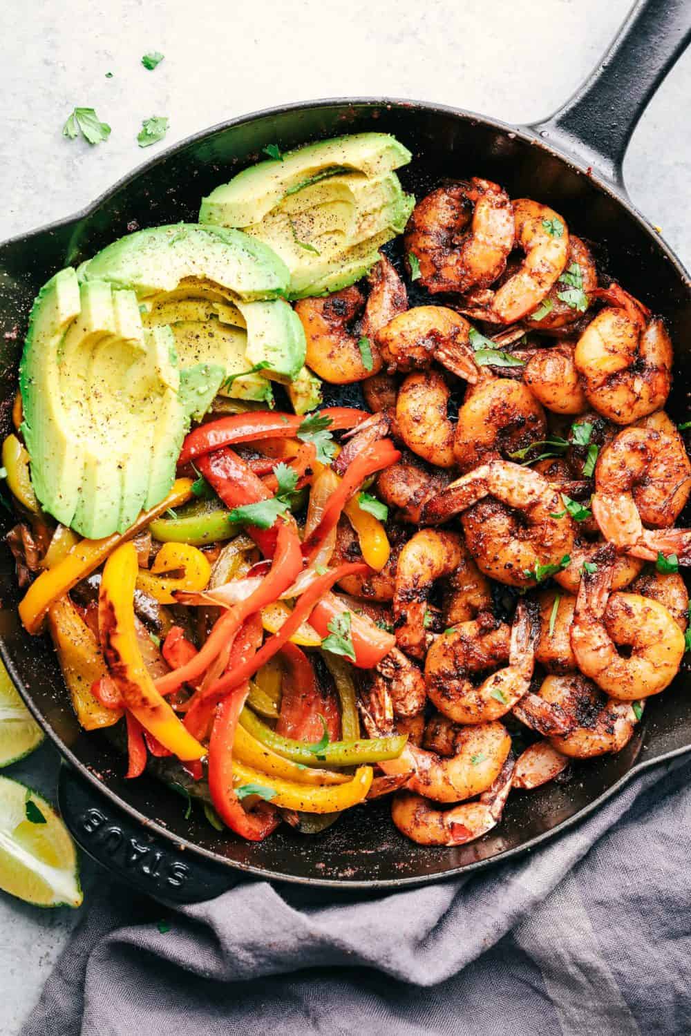 20 Minute Skillet Blackened Shrimp Fajitas are such an easy and flavorful meal packed with blackened shrimp, peppers and onion. This classic meal is perfect served up in tortillas with avocado and chopped cilantro! 20 Minute Skillet Blackened Shrimp Fajitas in a cast iron skillet.