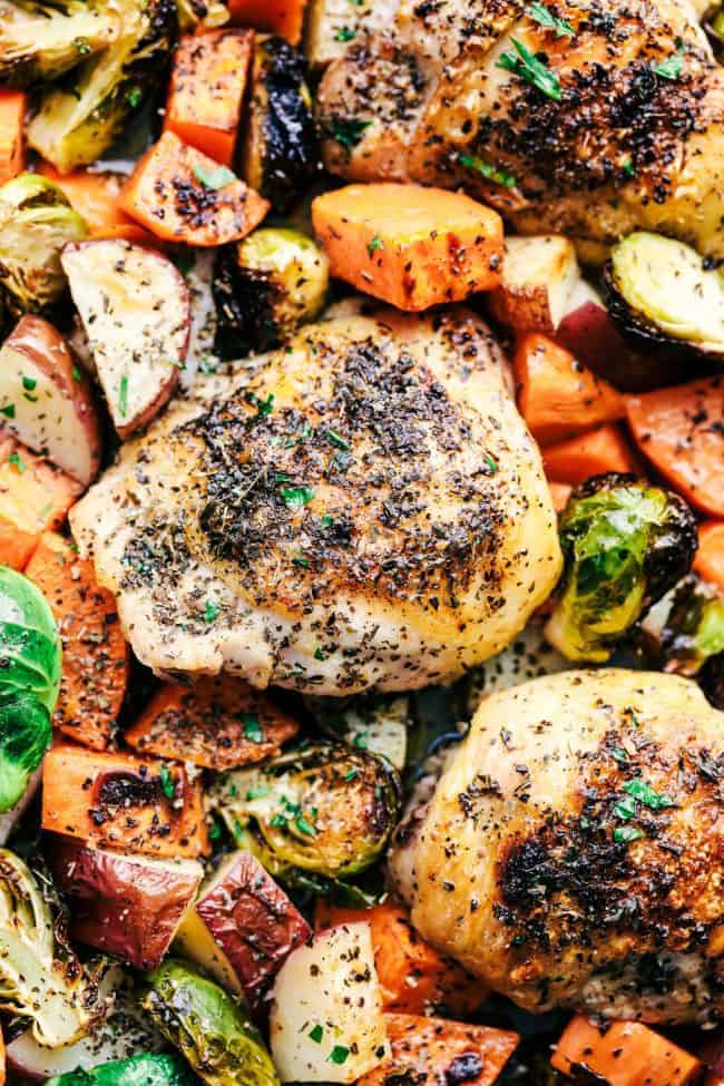 Sheet Pan Roasted Garlic Butter Herb Chicken is such a rustic and incredible dish. Surrounded by sweet potatoes and brussels sprouts this meal is loaded with amazing garlic butter herb flavor! Close up of Roasted Garlic Butter Herb Chicken with Potatoes and Brussels Sprouts