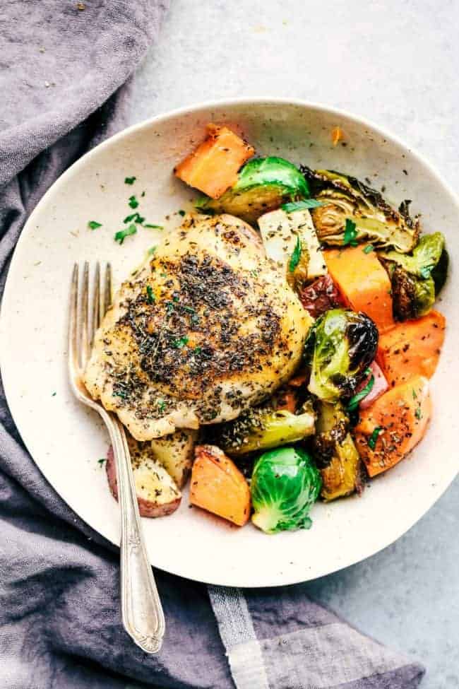 Sheet Pan Roasted Garlic Butter Herb Chicken is such a rustic and incredible dish. Surrounded by sweet potatoes and brussels sprouts this meal is loaded with amazing garlic butter herb flavor! Sheet Pan Roasted Garlic Butter Herb Chicken with Potatoes and Brussels Sprouts on a plate.