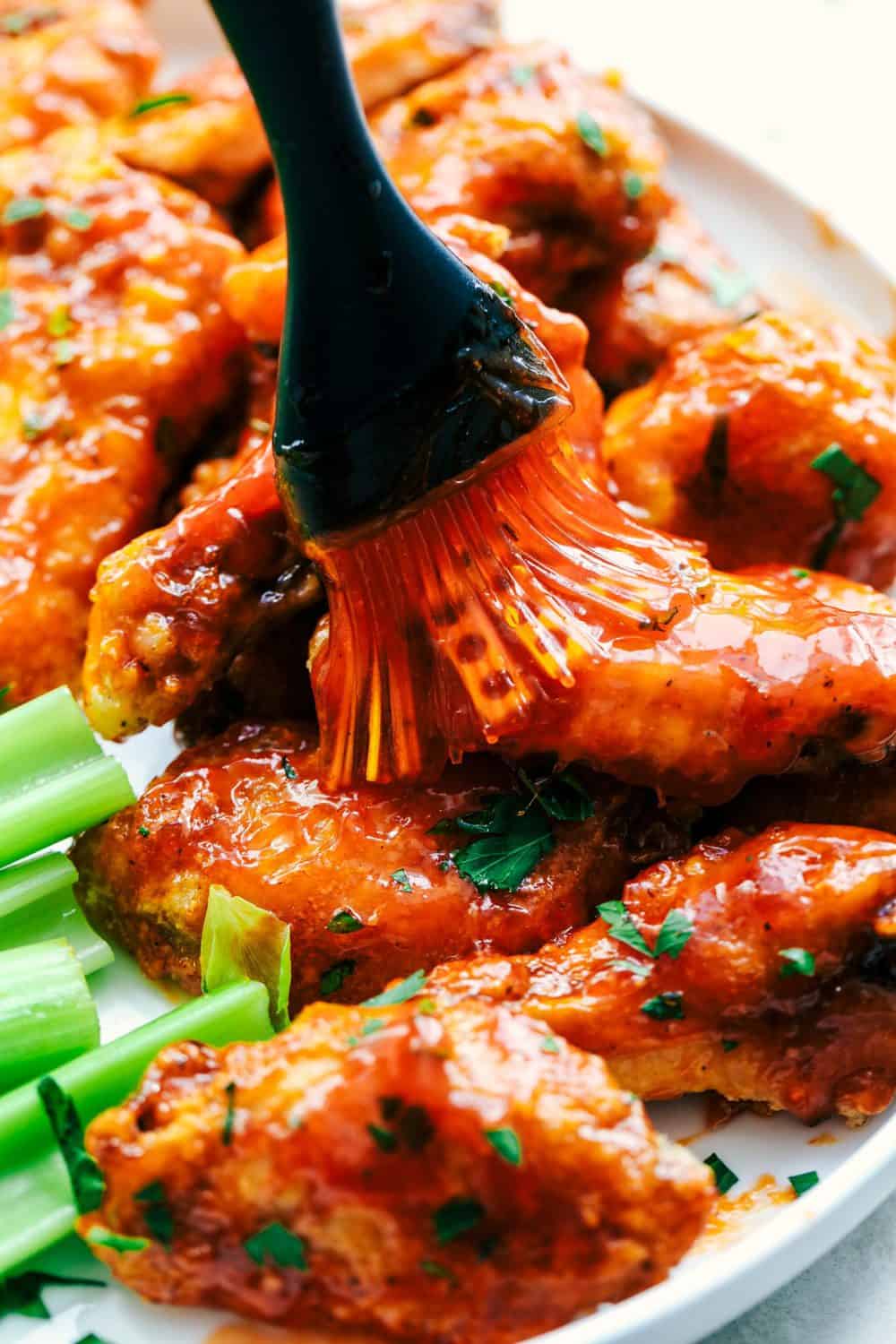 Baked Sticky Honey Garlic Buffalo Wings are baked to crispy perfection and topped with the most amazing honey garlic buffalo sauce. These are finger licking good! Baked Sticky Honey Garlic Buffalo Wings being brushed with sauce.