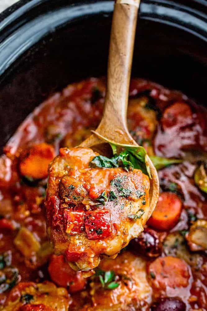 Slow Cooker Chicken Cacciatore - an easy crockpot meal loaded with tender chicken, tomatoes, bell peppers, kale, carrots and sliced mushrooms. Hearty, comforting and bursting with flavor. Scooping up slow Cooker Chicken Cacciatore with a wooden spoon.
