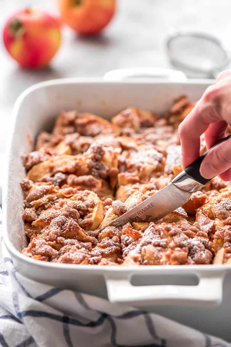 Overnight Cinnamon Apple French Toast Casserole is the perfect autumn breakfast to wake the family up to!ย Overnight Cinnamon Apple French Toast Casserole in a white baking dish.