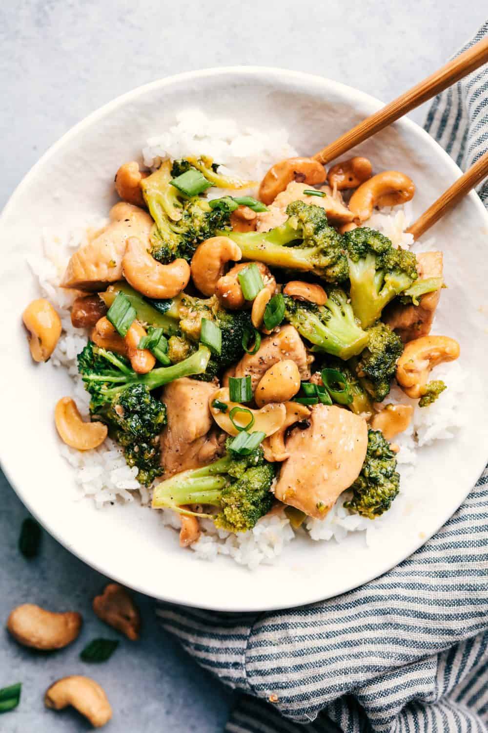 Garlic Chicken and Broccoli Cashew Stir Fry is the easiest meal to make and only requires one skillet! This meal is packed with amazing flavor and crunchy cashews and will become an instant favorite! Garlic Chicken and Broccoli Cashew Stir Fry with white rice and chopsticks.