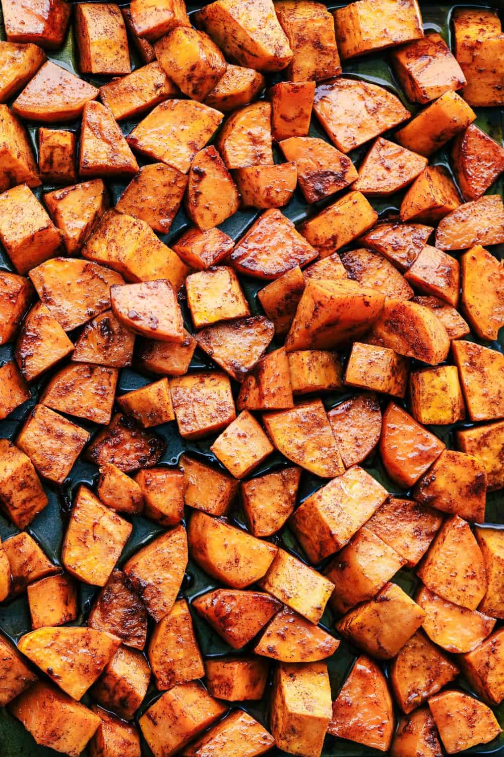 Roasted Honey Cinnamon Butter Sweet Potatoes get roasted with the incredible flavor of cinnamon honey butter to create the absolute perfect side dish! Roasted Honey Cinnamon Butter Sweet Potatoes spread out on a pan.