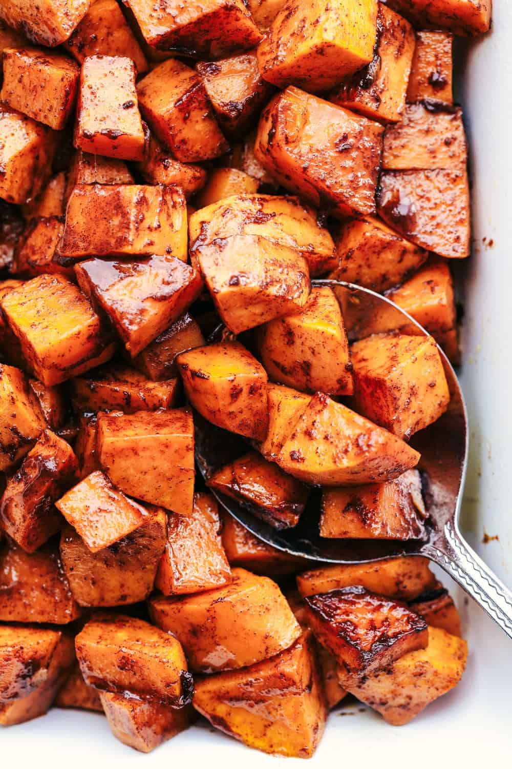 Roasted Honey Cinnamon Butter Sweet Potatoes get roasted with the incredible flavor of cinnamon honey butter to create the absolute perfect side dish! Spoonful of Roasted Honey Cinnamon Butter Sweet Potatoes.