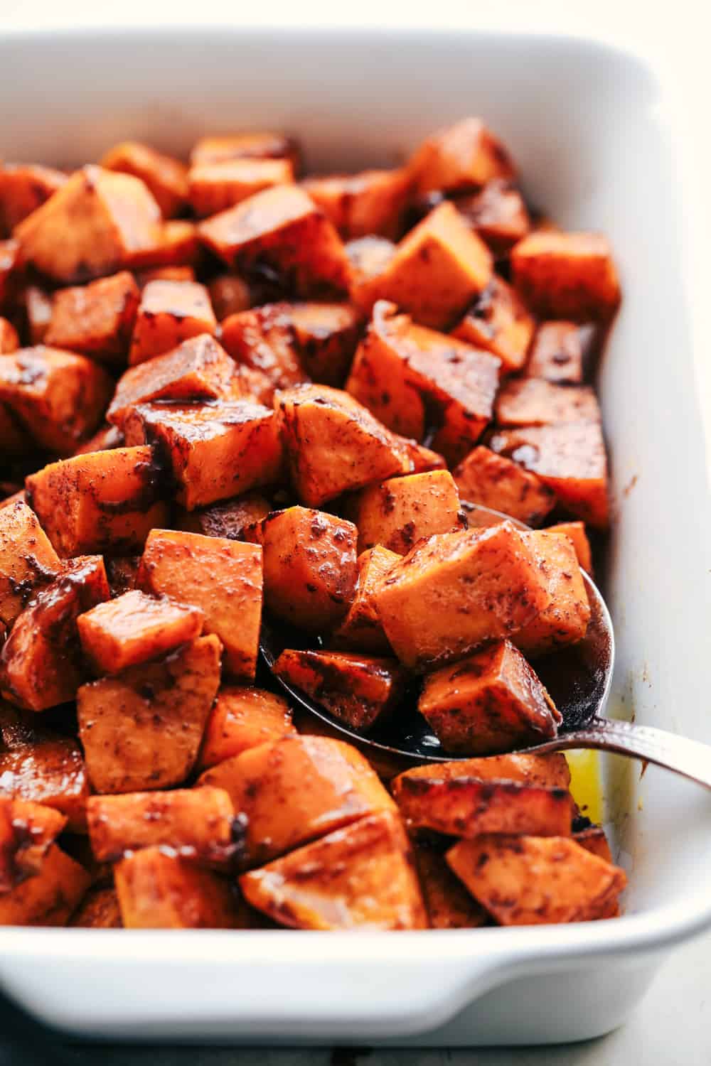Roasted Honey Cinnamon Butter Sweet Potatoes get roasted with the incredible flavor of cinnamon honey butter to create the absolute perfect side dish! Spoonful of Roasted Honey Cinnamon Butter Sweet Potatoes.