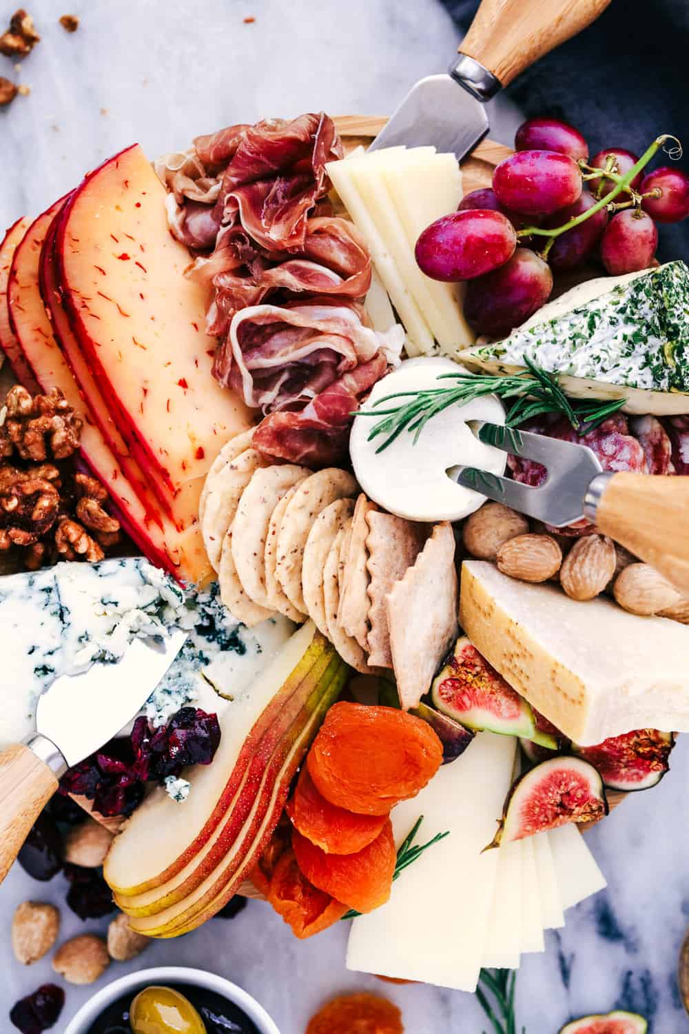 How to Make an Easy Cheese Board filled with meats, cheeses, nuts, and fruit. This makes a beautifulย presentation at any gathering!ย Cheese Board filled with meats, cheeses, nuts, and fruit.