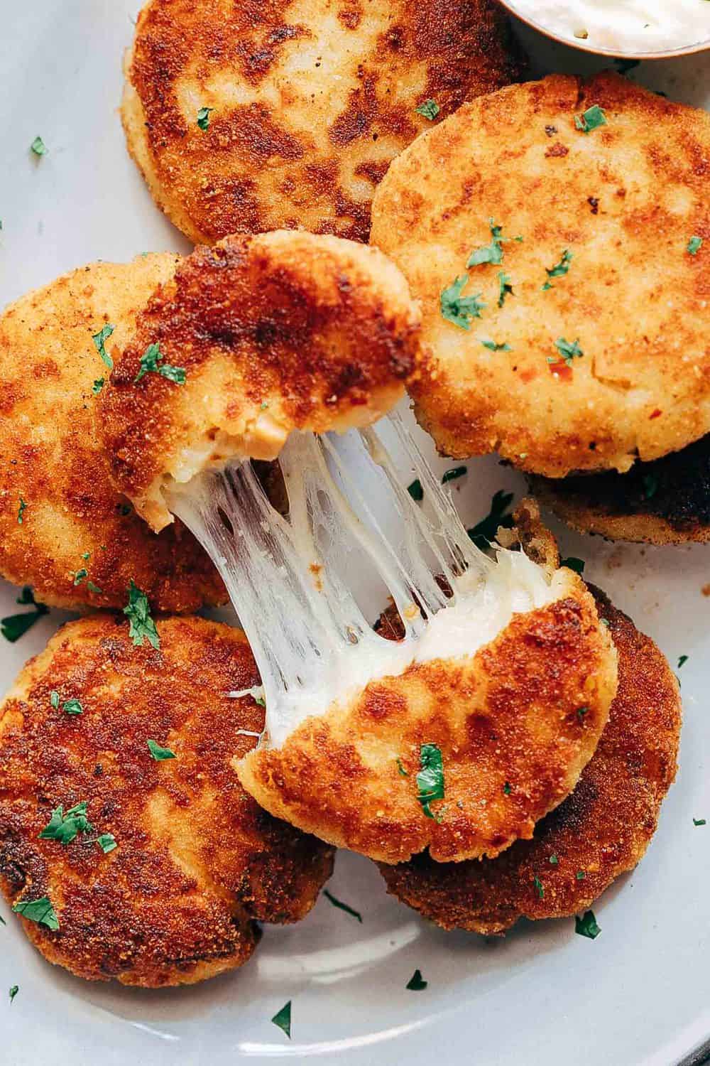 These ham mashed potato cakes are the most amazing way to use leftover mashed potatoes. They are incredibly cheesy and make for a delicious snack or appetizer! Stretchy cheesy shot of ham mashed potato cakes to show texture