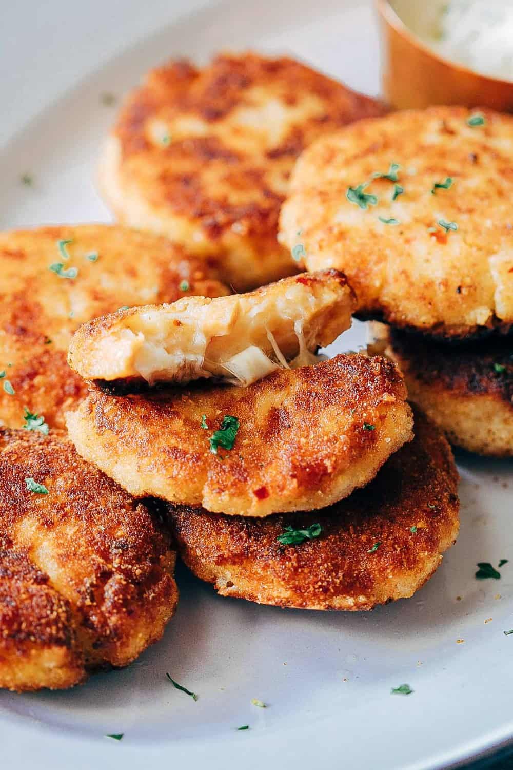 These ham mashed potato cakes are the most amazing way to use leftover mashed potatoes. They are incredibly cheesy and make for a delicious snack or appetizer! Stretchy cheesy shot of ham mashed potato cakes to show texture