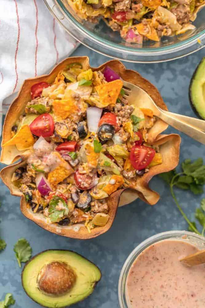 Thisย Creamy Taco Salad is the ultimate fun party meal for game day. It's simple, perfect for a crowd, and oh so delicious! Creamy Taco Salad with a cut avocado and bean dip.