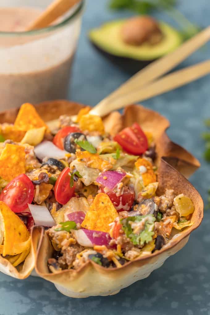 Thisย Creamy Taco Salad is the ultimate fun party meal for game day. It's simple, perfect for a crowd, and oh so delicious! Creamy Taco Salad with bean dip in the background.