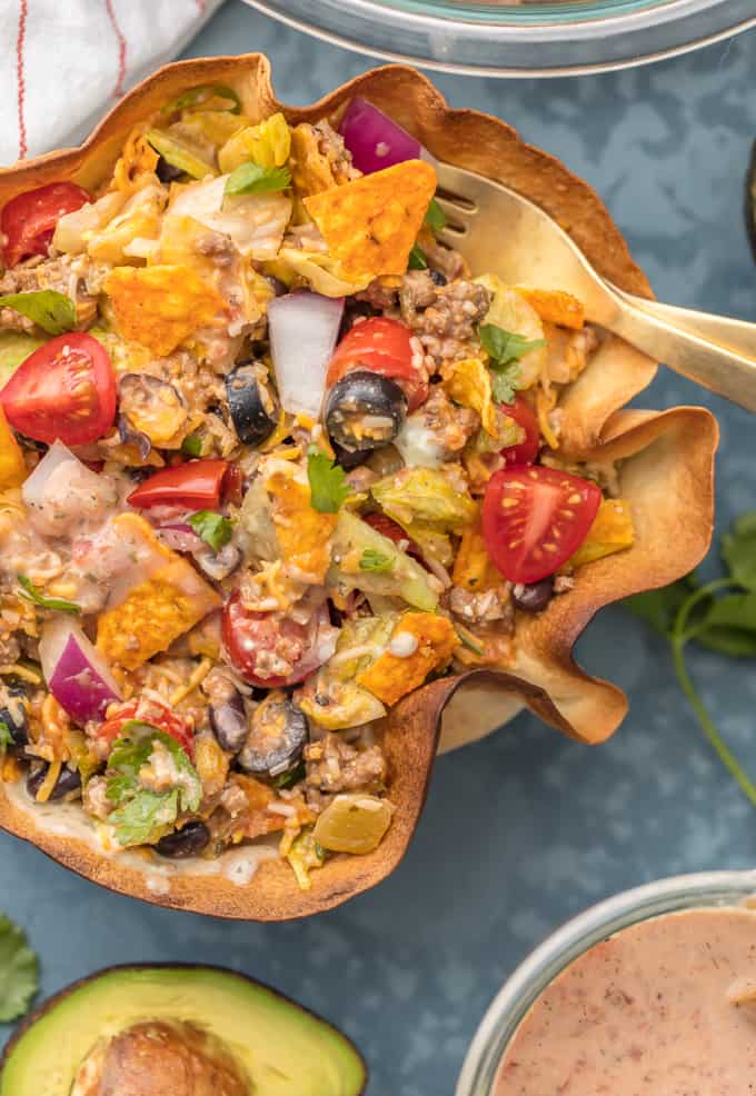 Thisย Creamy Taco Salad is the ultimate fun party meal for game day. It's simple, perfect for a crowd, and oh so delicious! Close up of Creamy Taco Salad in a decorative wooded bowl.