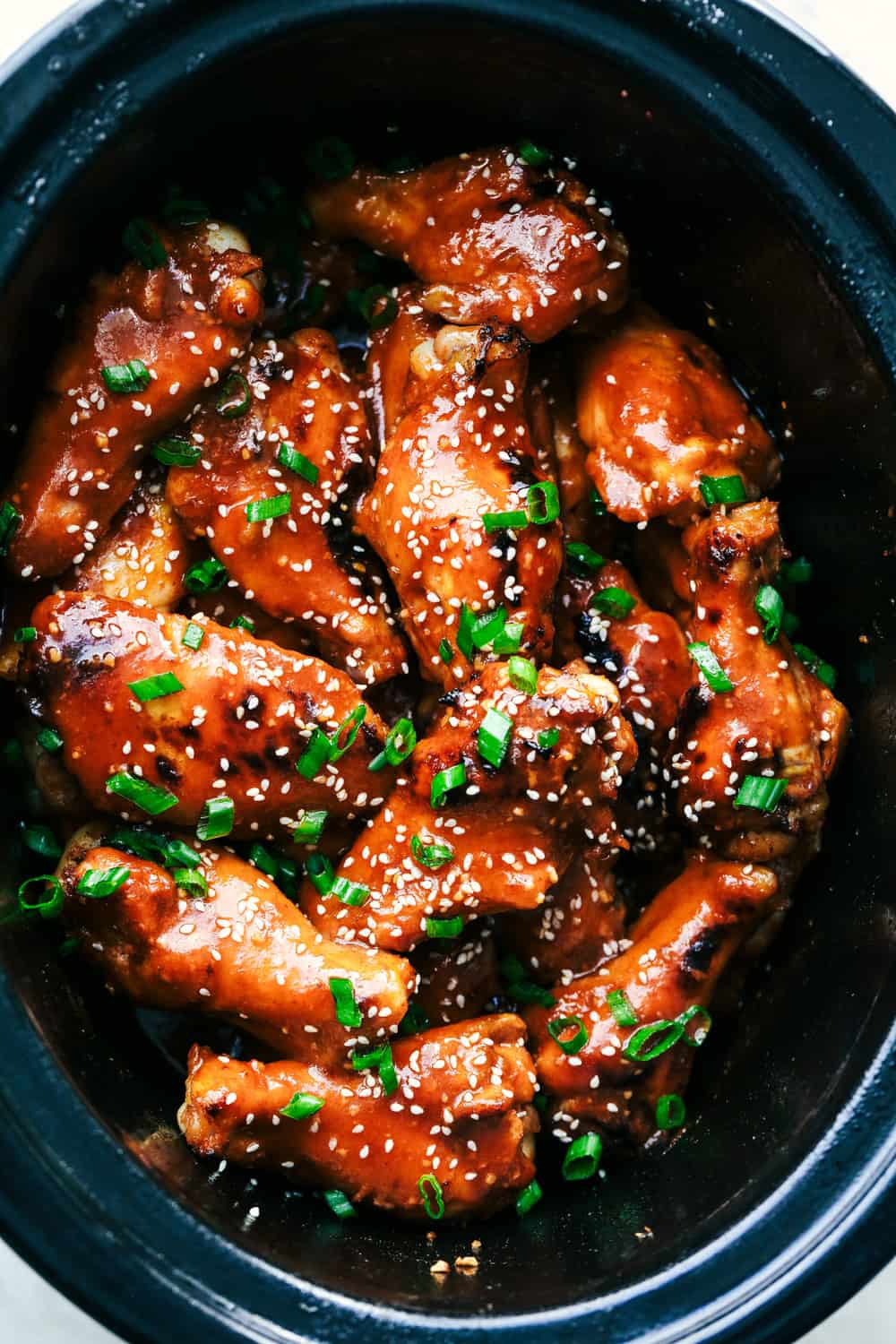 Slow Cooker Honey Garlic Sriracha Wings are super easy to make and have amazing sweet and spicy flavor! They are fall off the bone tender and will be the hit at any party! Slow Cooker Honey Garlic Sriracha Wings in a crock pot.