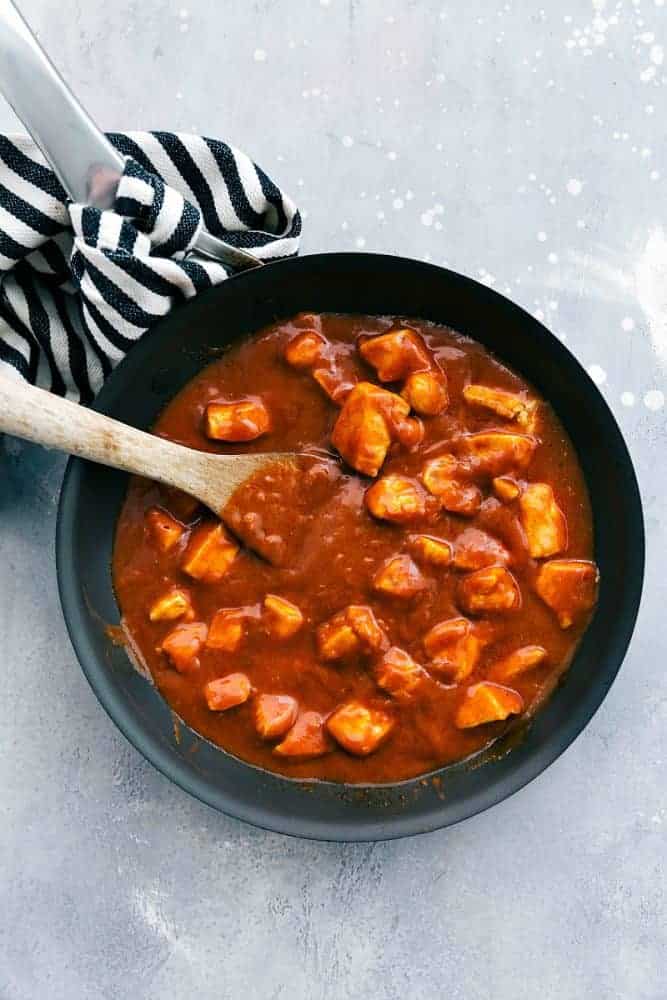 This Easy Butter Chicken comes together so easily with the help of Patakโsยฎ Butter Chicken Curry Simmer Sauce and diced chicken. Serve it over rice and you have a flavorful and amazing meal for your family ready in under 30 minutes!ย Easy Butter Chicken in a black pan with a wooden spoon.