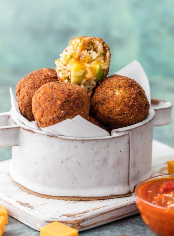 This Bacon Broccoli Cheese Arancini is a fun and unique appetizer fit for starting any delicious meal at home. Much easier than you would think and bursting with flavor. One Bacon Broccoli Cheese Arancini cut in half and stacked on others.