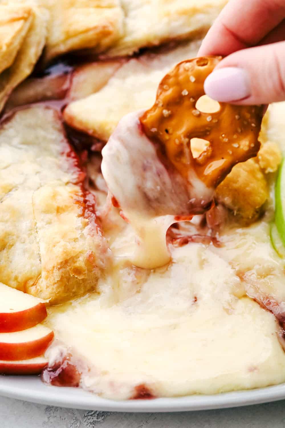 Raspberry Baked Brie is the perfect holiday appetizer with just FOUR ingredients! It is quick and easy to make and a tried and true favorite! Creamy Baked Brie with Raspberries on a pretzel chip.