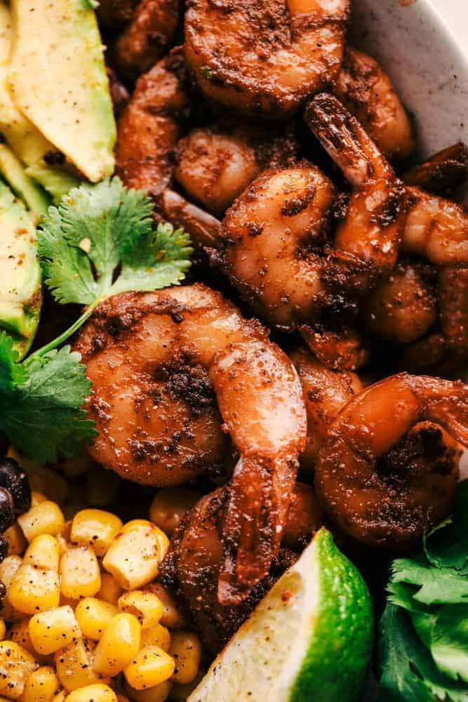 Blackened Shrimp Avocado Burrito Bowls are the perfect way to ring in the New Year with big bold flavor and a healthy meal! These are packed with blackened shrimp, brown rice, corn, black beans, and avocado. They are also great for meal prep! Blackened Shrimp Avocado Burrito with cilantro and lime for garnish.