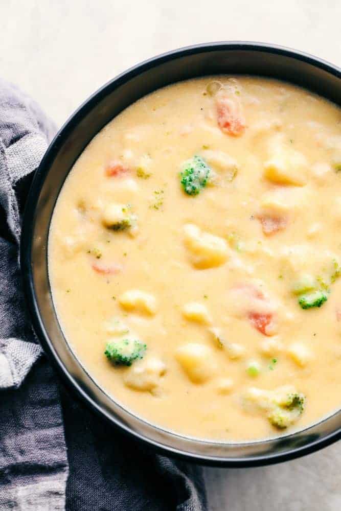 Cheesy Vegetable Soup is jam packed with tender vegetables in a creamy cheesy soup. This soup has amazing flavor and is so comforting in the winter! Cheesy Vegetable Soup in a black bowl.