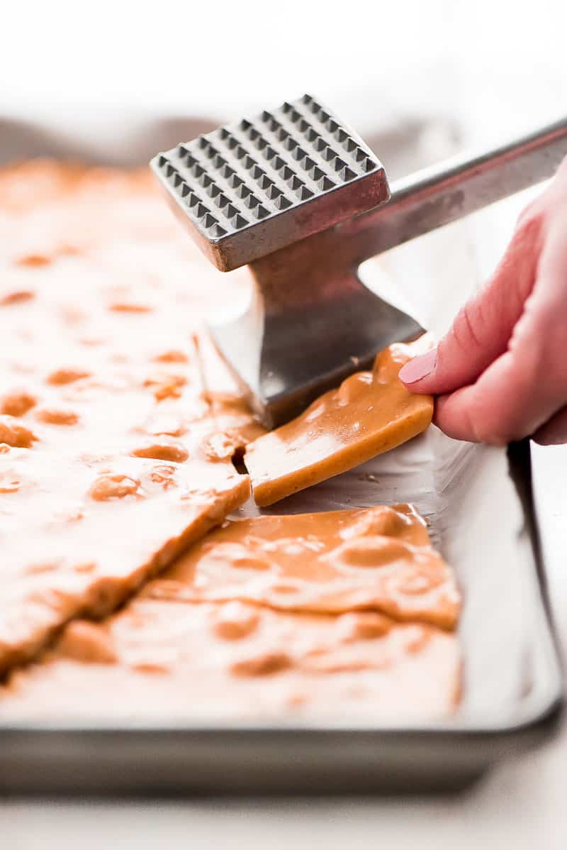 Peanut Brittle is a classic buttery and crunchy candy that no one will be able to resist munching on. It's perfect for packaging and giving away during the holidays. peanut brittle being broken apart with a meat tenderizer.