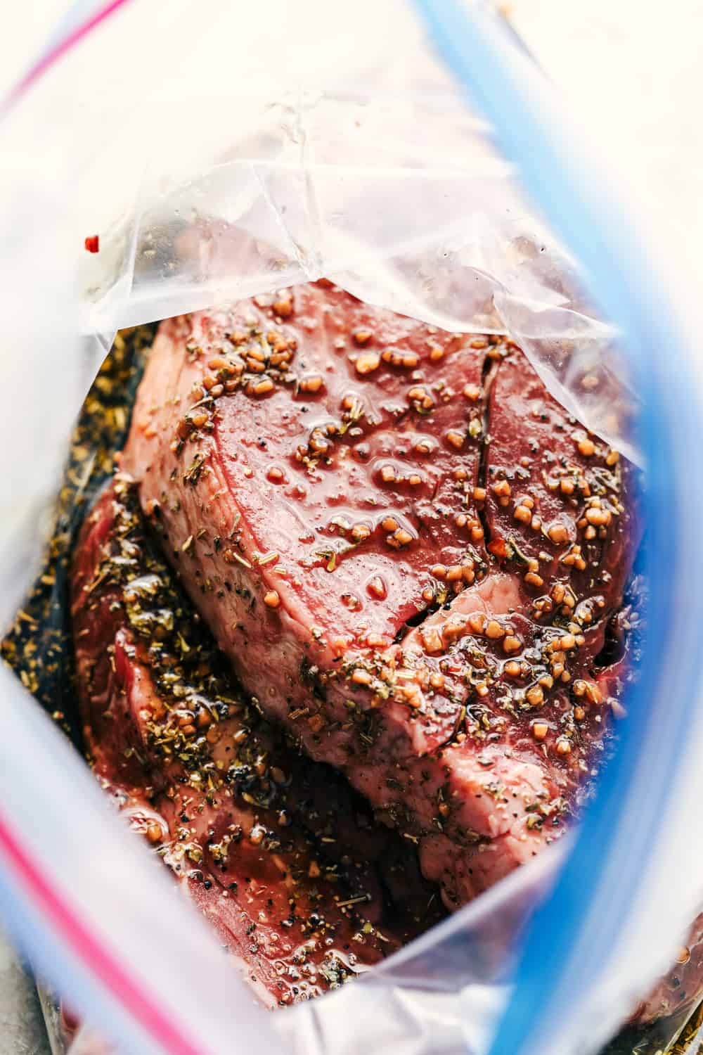 Perfectly Juicy Grilled Steak gets marinaded in the best flavor and grilled to juicy perfection! Learn all of the tips and tricks to grill the BEST steak every single time! Steak marinating in ziploc bag.