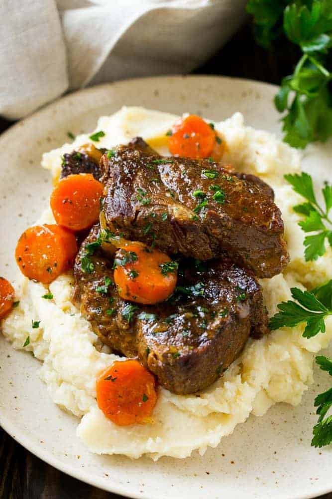 These fork tender root beer glazed short ribs are the perfect meal for a cold winter night. Serve them over mashed potatoes for a dinner that's sure to earn rave reviews from family and friends! Root beer glazed short ribs and cooked carrots over mashed potatoes.