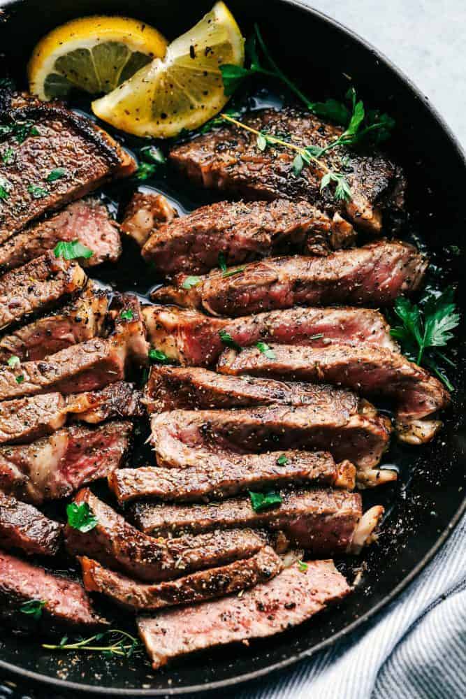 This steak marinade is one of the top recipes on my site! Itโs my go-to for turning tough, budget-friendly cuts into juicy, flavor-packed steaks that practically melt in your mouth. Cut steak with steak marinade in a skillet with two slices of lemon.