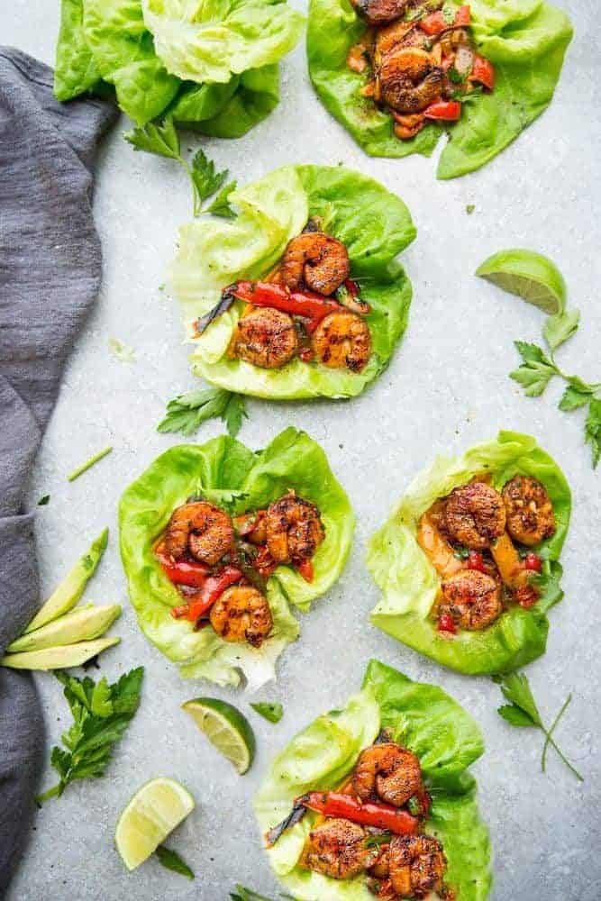 These Cilantro Lime Shrimp Lettuce Wraps are fresh, flavorful and super easy to make! They make the perfect handheld appetizers or a light and healthy low-carb lunch or dinner! Cilantro Lime Shrimp Lettuce Wraps with sliced lime on the side.