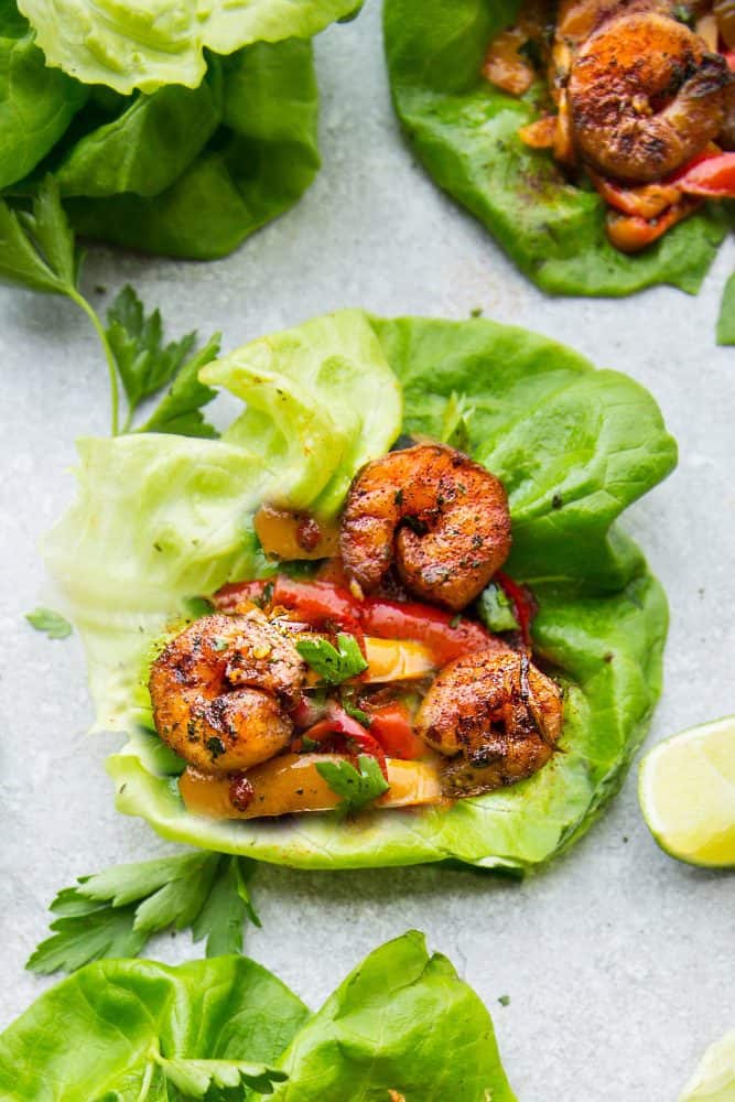 These Cilantro Lime Shrimp Lettuce Wraps are fresh, flavorful and super easy to make! They make the perfect handheld appetizers or a light and healthy low-carb lunch or dinner! Close-up of one cilantro lime shrimp lettuce wrap.