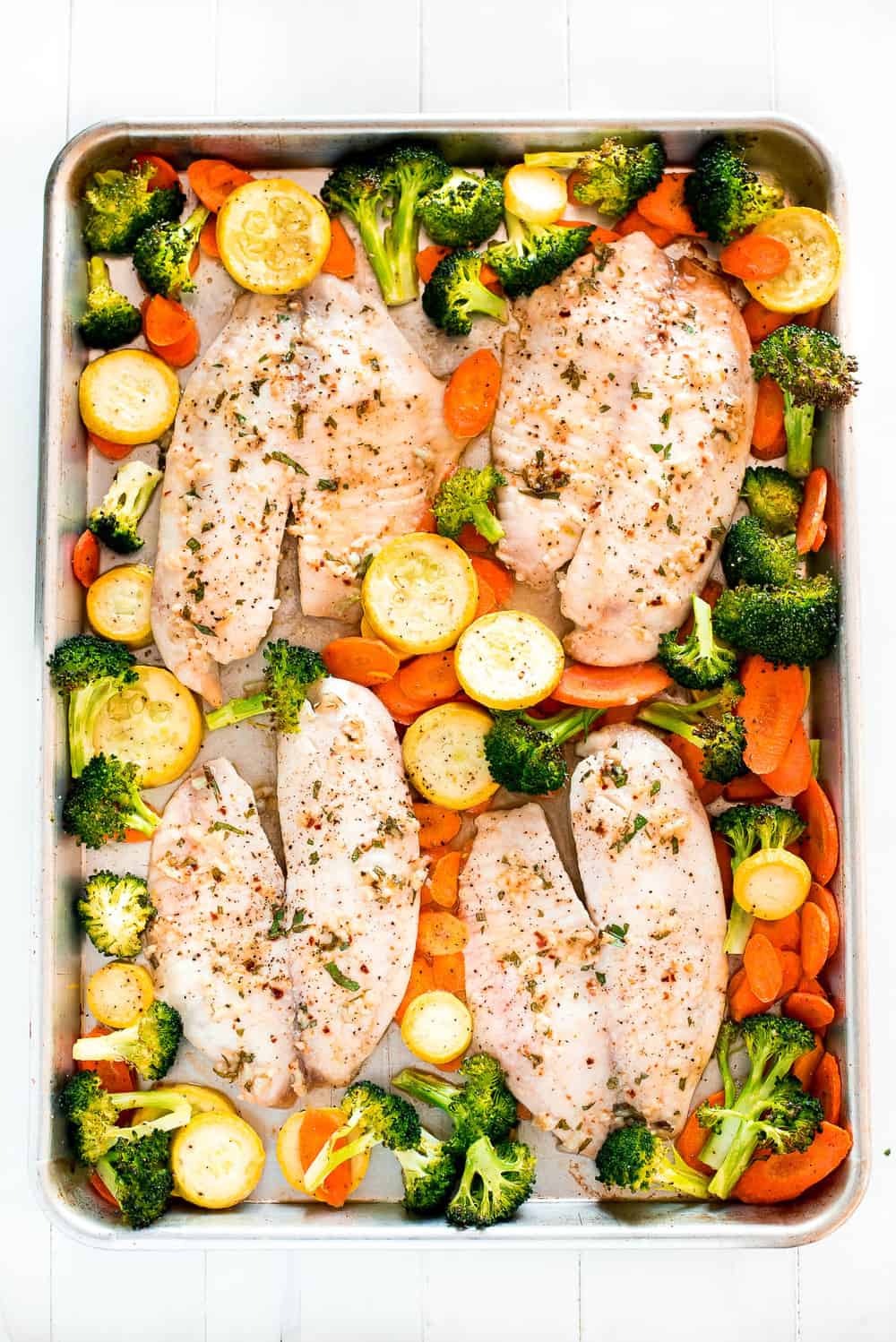 Baked Tilapia and Roasted Veggies is a low calorie and high protein dish that comes together in less than 25 minutes! Light and tasty in every bite!ย Baked Tilapia and Roasted Veggies on a pan