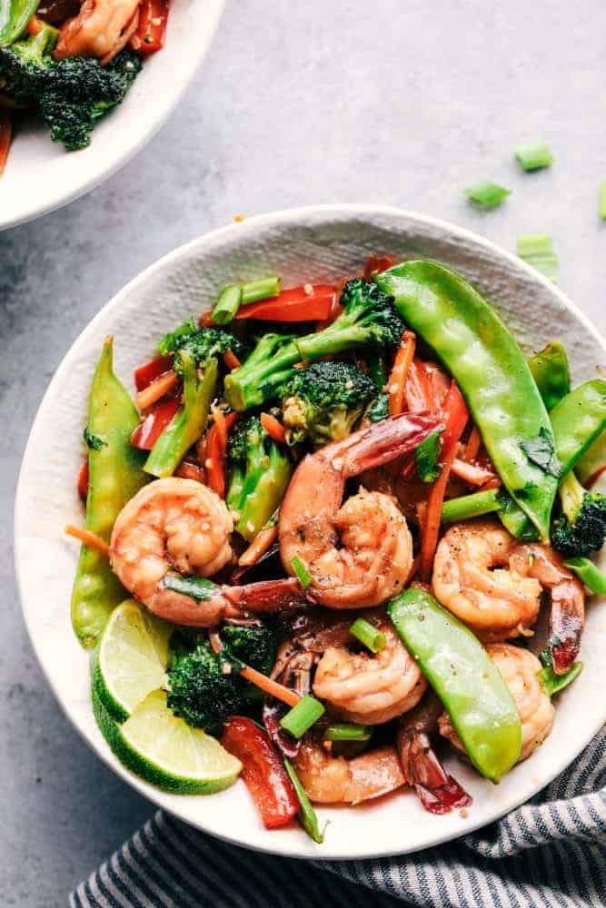 Some nights you just need dinner on the tableย fast! Thatโs when this garlic shrimp stir fry saves the day. Juicy shrimp, crisp veggies, and the BEST garlicky sauce all come together in 20 minutes. Garlic shrimp stir fry served in a bowl.