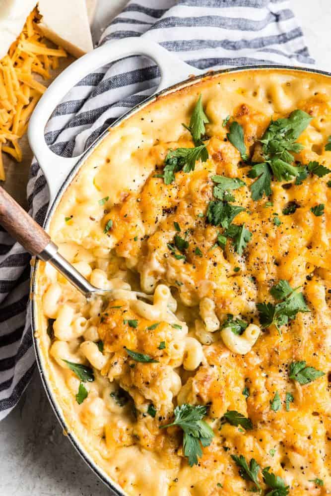 This Baked Macaroni and Cheese comes together quick and easy. Homemade cheese sauce generously covers noodles and is baked to a rich, bubbly, golden brown perfection. When served with a hearty side of veggies, this indulgent dish becomes the perfect weeknight meal. Baked Macaroni and Cheese in a pot with spoon.