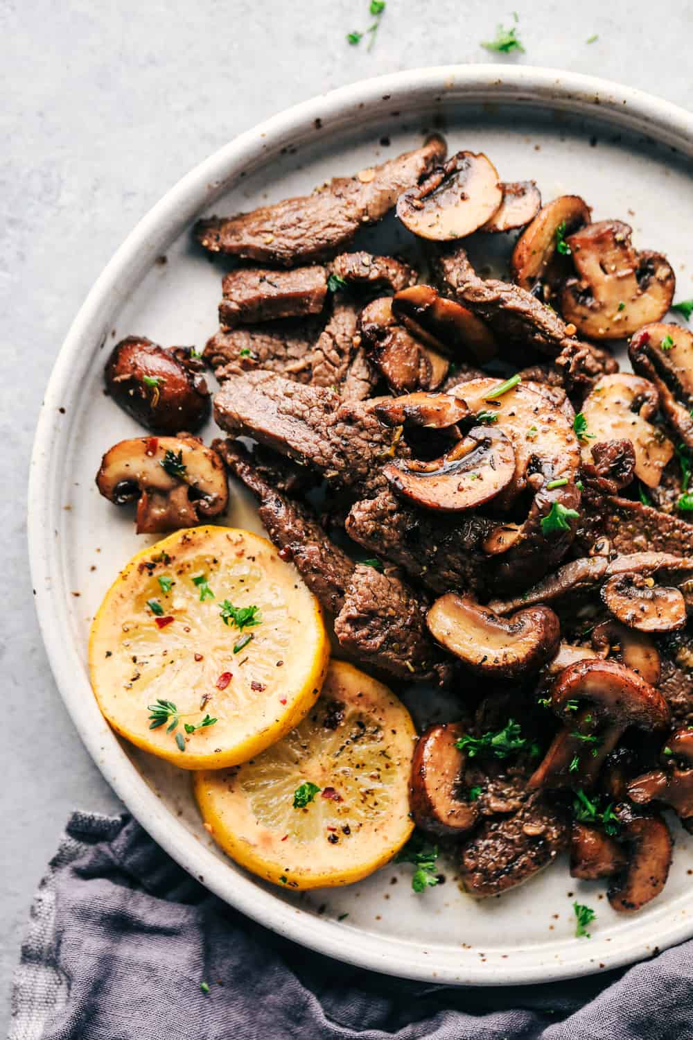 Lemon Garlic Butter Flank Steak with Mushrooms is tender, juicy flank steak cooked in a buttery, lemon garlic sauce mixed with mushrooms for the perfect combination. It is cooked in a skillet to tender perfection and a meal that everyone will love! Lemon Garlic butter flank steak with mushrooms on a plate