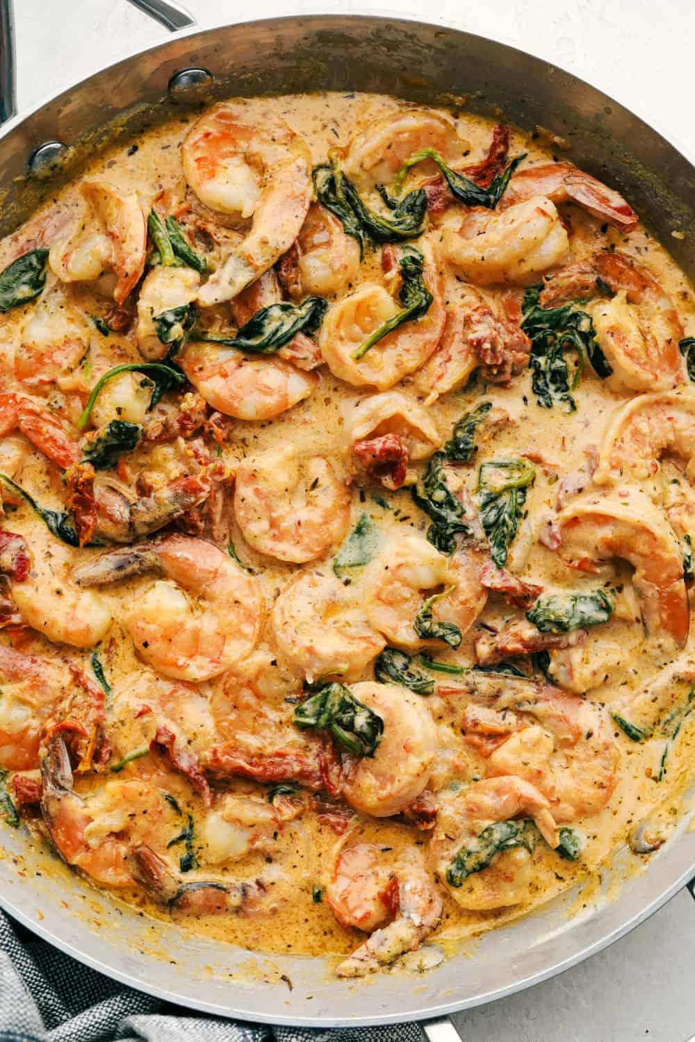 Tuscan Garlic Shrimpย is the most amazing creamy shrimp dish. A creamy garlic parmesan sauce with spinach and sun-driedย tomatoesย creates an unforgettable restaurantย qualityย meal right at home! Tuscan Garlic Shrimp in a pan ready to eat.