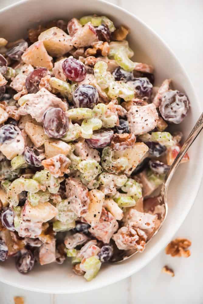 This Waldorf Chicken Salad is a refreshing and filling dish loaded with fruit, veggies, and nuts. It comes together quickly and packs up well for taking to work or even a picnic. A large bowl of Waldorf Chicken Salad sprinkled with pepper.